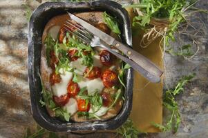 Pizza mit Tomaten und Rucola foto