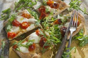 Pizza mit Tomaten und Rucola foto