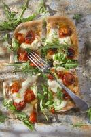 Pizza mit Tomaten und Rucola foto