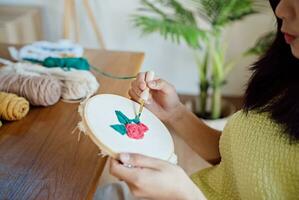 schlagen Nadel. asiatisch Frau Herstellung handgemacht Hobby Stricken im Studio Werkstatt. Designer Arbeitsplatz handgemacht Kunst Projekt DIY Stickerei Konzept. foto