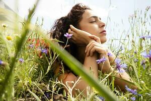 Mädchen Lügen Nieder und entspannt im ein Feld von Blumen foto