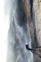 ein Person auf ein Seil Klettern oben ein Wasserfall foto