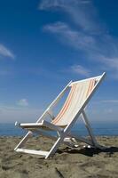 ein Strand Stuhl auf das Sand mit ein Blau Himmel foto