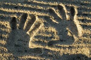 ein Hand drucken im das Sand mit zwei Hände foto