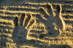 ein Hand drucken im das Sand mit zwei Hände foto