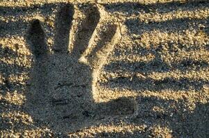 ein Hand drucken im das Sand mit zwei Hände foto