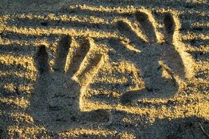 ein Hand drucken im das Sand mit zwei Hände foto