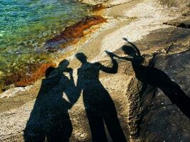 Schatten von zwei Menschen auf Felsen in der Nähe von Wasser foto