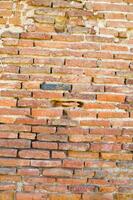 ein alt Backstein Mauer mit ein Loch im es foto