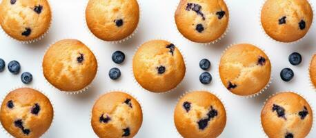 Muffins mit Blaubeeren vereinbart worden auf ein Weiß Hintergrund, fotografiert von ein oben Aussicht mit Raum foto