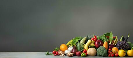 ein Essen Konzept repräsentiert durch ein Anzeige von frisch Früchte und Gemüse auf ein grau Hintergrund, foto
