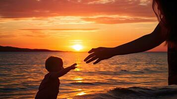 ein Kind und Mutter s Hände berühren beim Sonnenuntergang durch das Strand foto