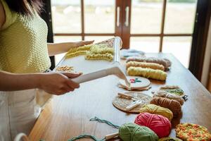 schlagen Nadel. asiatisch Frau Herstellung handgemacht Hobby Stricken im Studio Werkstatt. Designer Arbeitsplatz handgemacht Kunst Projekt DIY Stickerei Konzept. foto