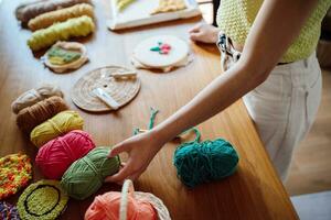 schlagen Nadel. asiatisch Frau Herstellung handgemacht Hobby Stricken im Studio Werkstatt. Designer Arbeitsplatz handgemacht Kunst Projekt DIY Stickerei Konzept. foto