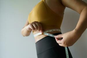Frau wollen zu verlieren Gewicht mit ein Zentimeter gestalten oben gesund Bauch Muskel und Diät Messung Taille mit messen Band nach Diät Gewicht Steuerung foto