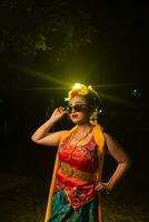 ein schön Sundanesisch Tänzer posiert und Tänze im ein glamourös Kleid und Schal im Vorderseite von das Bühne Licht foto