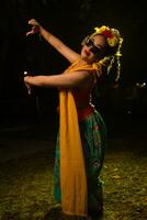 ein traditionell indonesisch Tänzer Tanzen mit das Körper Verdrehen auf Bühne foto