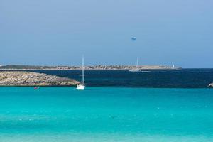 Boote vertäut an der Küste von Ses Illetes Strand auf Formentera, Balearen in Spanien.
