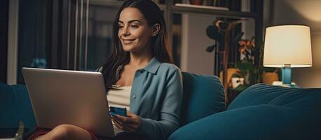 Frau Einkaufen online lächelnd mit Laptop auf Couch beim Zuhause foto