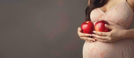 schwanger Frau mit Apfel zum Bauch auf grau Studio Hintergrund Ernährung und Schwangerschaft Konzept Banner mit Kopieren Raum foto