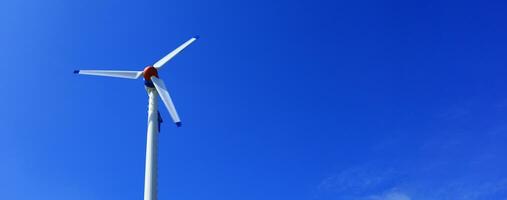 das Wind Turbine erzeugt ein ökologisch freundlich Elektrizität im das hell Blau Himmel. foto