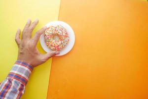 Hand pflücken frische bunte Donuts auf farbigem Hintergrund foto
