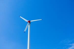 das Wind Turbine erzeugt ein ökologisch freundlich Elektrizität im das hell Blau Himmel. foto