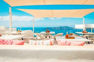 Cafe auf das Terrasse mit Blick auf das Meer. Santorini Insel, Griechenland. hervorragend Sommer- Stimmung, draussen Restaurant. romantisch Schwingungen, Sommer- Farben unter Weiß Zelt und Blau Himmel foto