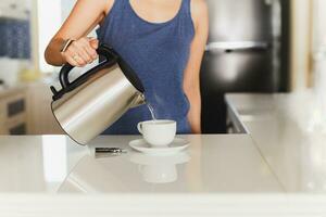 Frau Gießen heiß Wasser von Kessel im Tasse drinnen. foto