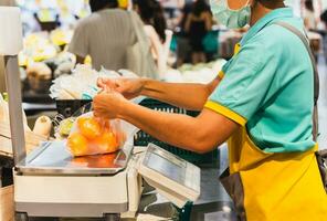 Lebensmittelgeschäft Geschäft Mitarbeiter Wiegen Orangen im Plastik Tasche auf Digital Waage. foto