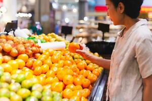 kaukasisch Frau Verbraucher beim Lebensmittelgeschäft Geschäft wählen Orange saftig Zitrusfrüchte. foto