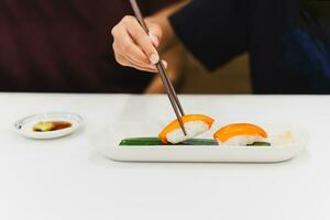 Hand mit Essstäbchen hält Sushi mit Lachs Fisch. foto