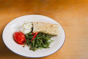 Rakete Salat mit Italienisch Burrata Käse und Tomate im Weiß Platte. foto