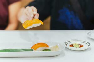 Hand mit Essstäbchen hält Sushi mit Lachs Fisch. foto