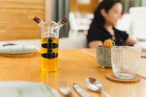 ein Glas Flasche mit Olive Öl und Balsamico Essig auf Abendessen Tisch. foto