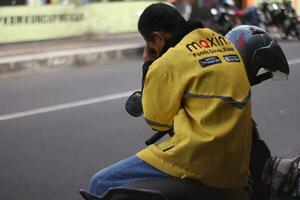 Magelang, Indonesien - - 07 31 ,2023-Treiber Maxime ist Sitzung auf ein Motorrad während warten zum Aufträge. foto