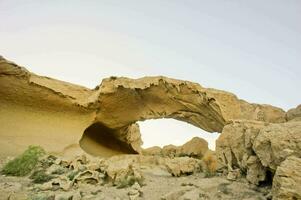 ein groß Felsen Formation im das Wüste mit ein Loch im es foto