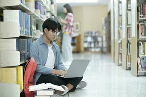 jung Universität Schüler mit Laptop zum online Lernen, suchen und Lernen beim Bibliothek. foto
