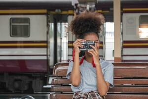 jung asiatisch afrikanisch Frau Reisender mit Rucksack im das Eisenbahn Zug Bahnhof, Reisender Mädchen Gehen Stand sitzen warten nehmen ein Bild auf Eisenbahn Plattform Zug Bahnhof. hoch Qualität Foto