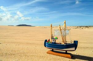 ein Spielzeug Boot sitzt auf das Sand foto