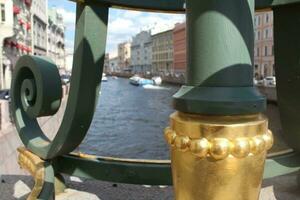 golden Metall Zaun auf ein Brückezu das Stadtbild auf das Damm von das Gribojedov Kanal im st. petersburg, Russland. foto