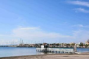 ein Seebrücke mit Boote auf das Wasser und ein Strand foto