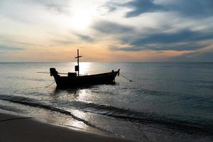 Silhouette eines kleinen Fischerbootes im Meer bei Sonnenaufgang