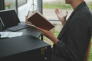 geschäftsleute und anwälte diskutieren vertragspapiere mit messingwaage auf dem schreibtisch im büro. gesetz, juristische dienstleistungen, beratung, justiz und gesetz konzeptbild mit filmkorneffekt foto