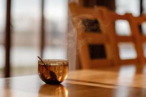 Tasse Tee mit Dampf auf Holztisch im Wohnzimmer. selektiver Fokus foto