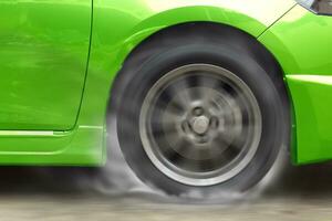 Grün Auto Rennen Spinnen Rad brennt Gummi auf Boden. foto