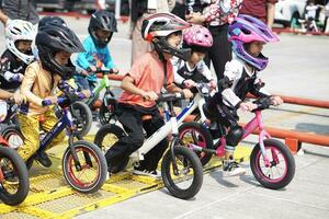 depok-indonesien, 29 07 2023 - - indonesisch Kinder von 2-5 Jahre alt bereit zu Rennen auf Balance Fahrrad im ein Parkplatz Bereich, Sportlichkeit Ausbildung. foto