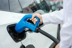 jung Geschäft Frau Auftanken ihr elektrisch Auto beim ein ev Laden Bahnhof. Konzept von ökologisch freundlich Fahrzeug. elektrisch Auto Konzept. Grün Reisen. foto