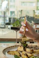 schließen oben von ein Gabel im ein Frau Hand Über ein Teller mit köstlich Essen im ein Restaurant foto