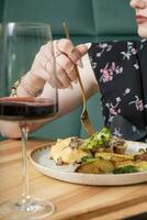 schließen oben von ein Gabel im ein Frau Hand Über ein Teller mit köstlich Essen im ein Restaurant foto